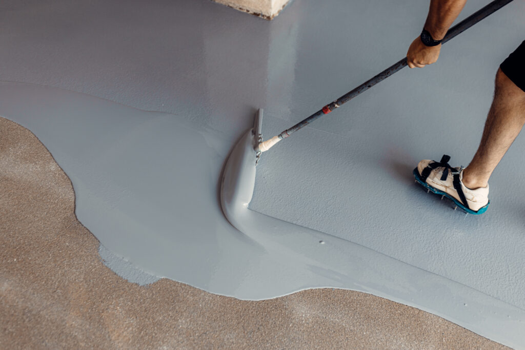 Contractor applying epoxy coating to price epoxy flooring installation
